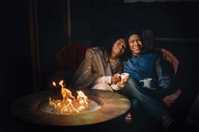 Two people sitting by a propane powered outdoor fireplace